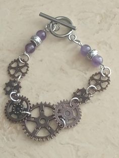 One of a Kind Steampunk Bracelet with Gear Charm and Dainty Round Purple Amethyst Beads. Size 6.5 wrist with Toggle Clasp. Great for any occasion. Steampunk Jewelry Bracelets, Steampunk Jewelry Ideas, Steampunk Armband, Steampunk Bracelet, Lemon Grove, Jewelry Piercing, Steampunk Watch, Steam Punk Jewelry, Body Jewelry Piercing