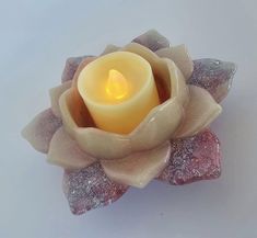 a lit candle sitting on top of a flower shaped object