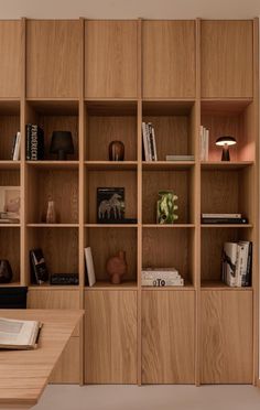 a wooden book shelf with books and other items on it, along with a lamp