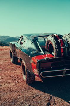 a red and black car with four tires on it's flatbed in the desert