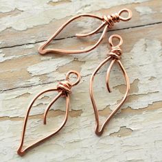 two pairs of copper earrings sitting on top of a wooden table