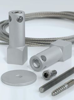 an assortment of metal parts including screws, nuts and wires on a white surface