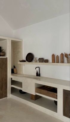 an empty room with shelves and vases on the wall next to eachother