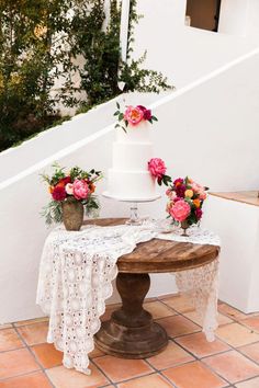 a white wedding cake sitting on top of a wooden table next to a planter