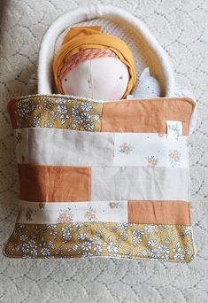 a stuffed doll is in a patchwork bag on the floor next to a pillow