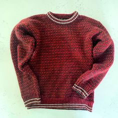 a red and black sweater hanging on a white wall