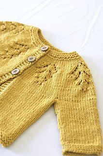 a knitted sweater with buttons on the front and back, sitting on a white surface