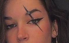 a woman with cross painted on her face and piercings around her eyes is looking at the camera