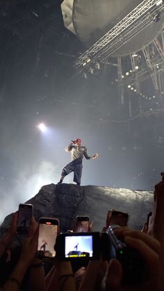 a man standing on top of a rock while holding a cell phone in his hand