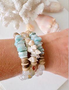 a woman's arm with bracelets and shells on it