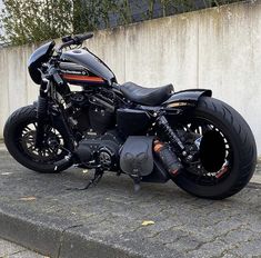 a black motorcycle parked next to a cement wall