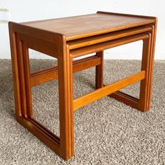 two wooden nesting tables sitting on top of carpeted floor next to each other in front of a white wall