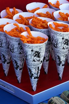 several cones filled with cheetos sitting on top of a red table next to each other