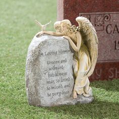 an angel figurine sitting on top of a stone next to a headstone