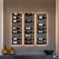 the wine bottles are lined up on the wall in front of the black cabinet and vases