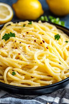 a plate of pasta with parmesan cheese and lemons in the background on a towel