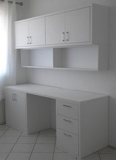 an empty white desk and cabinets in a room with tile flooring on the floor