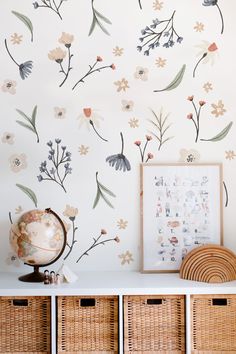 a wall with flowers painted on it next to wicker baskets and a framed photograph