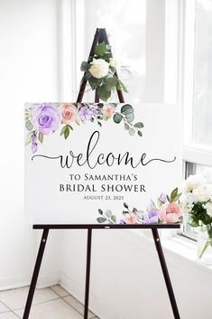 a welcome sign with flowers on it in front of a window