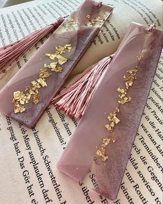 two pink and gold tassels sitting on top of an open book