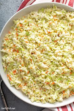 coleslaw salad in a white bowl with carrots and celery on the side