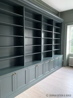 an empty room with gray bookcases and wood floors