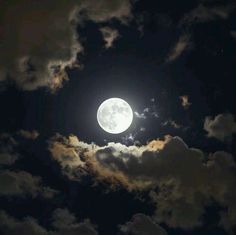 the full moon is shining brightly in the night sky with clouds and dark blue skies