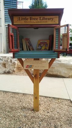 the little free library is located on the side of the road in front of a building