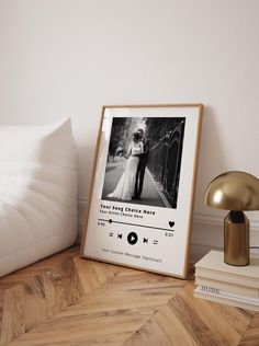 a photo frame sitting on top of a wooden floor next to a lamp and pillows