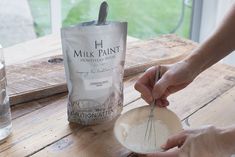 a person is mixing something in a bowl on a wooden table next to a can