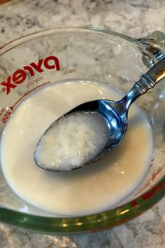 a glass bowl filled with white liquid and a spoon