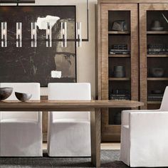 a dining room table with white chairs and an art piece on the wall behind it