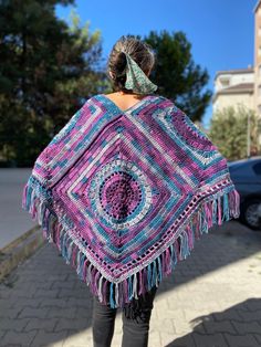 a woman is walking down the street with a colorful shawl