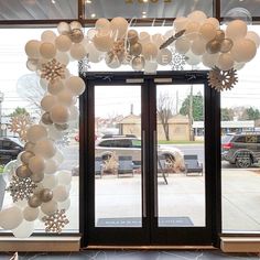 an entrance to a store with balloons and snowflakes hanging from the front door