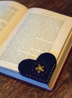 an open book sitting on top of a wooden table next to a heart shaped object