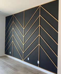 an empty room with black walls and gold lines on the wall, along with wood flooring