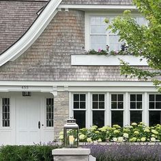 a house with flowers in the front yard and a lantern on the side of it