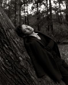 a man laying on top of a tree next to a forest filled with lots of trees