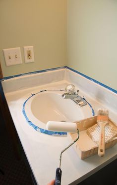 a person is painting the edge of a bathroom sink