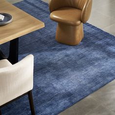 a blue rug with a chair and table in the background