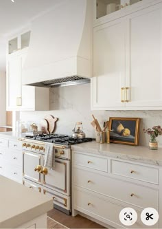 a kitchen with white cabinets and gold trim on the stove top, along with brass pulls