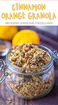 a glass jar filled with granola sitting on top of a wooden table next to an orange