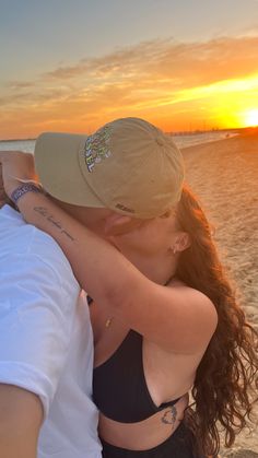 a man and woman hug on the beach at sunset