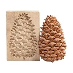 two pine cones are next to each other on a wooden block, one is carved into the shape of a pine cone