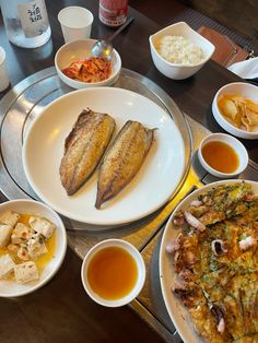 a table topped with plates of food next to bowls of sauces and condiments