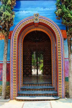 an entrance to a colorful building with trees in the background