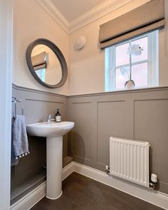 a bathroom with a sink, mirror and radiator next to a window in the wall