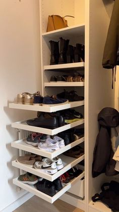 an organized closet with shoes and handbags on the shelves in front of it,