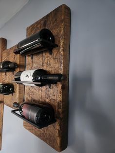 a wooden wine rack holding several bottles of wine on it's sides and hanging from the wall