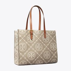 T Monogram is a classic pattern inspired by Pennsylvania Dutch quilting. The collection speaks to the timelessness of great style.  The tote is crafted in contrast embossed leather with an adjustable shoulder strap. Each side of the tote features an inverse color combination, creating two looks in one. Lined in soft microsuede with an interior laptop sleeve, every detail is considered, with special attention to function and versatility.   Crafted in partnership with a Leather Working Group-certi Coated Canvas Monogram Print Tote Shoulder Bag, Monogram Print Coated Canvas Tote Shoulder Bag, Classic Tan Bags In Signature Coated Canvas, Classic Shoulder Bag With Double Handle And Embossed Logo, Classic Monogram Print Bag For Everyday Use, Classic Tan Coated Canvas Shoulder Bag, Classic Monogram Print Shoulder Bag, Tan Monogram Print Shoulder Bag, Everyday Tan Monogram Print Shoulder Bag